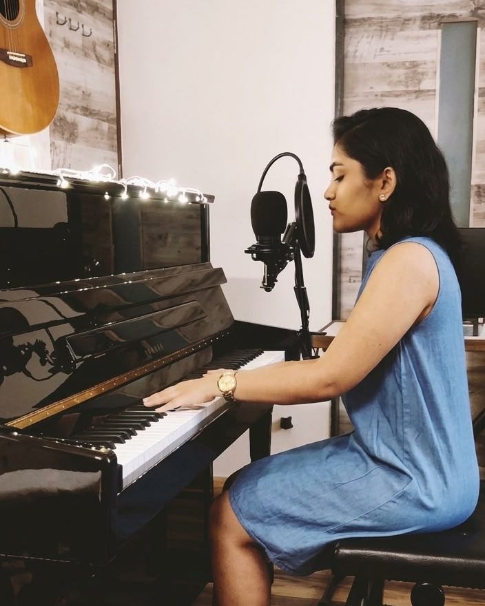 Shrusti Vernekar playing an upright piano in her studio
